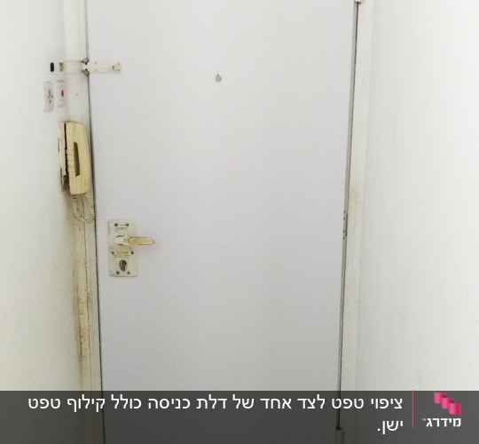 דלת לבנה עם ידית ומנעול, טלפון קיר בצד